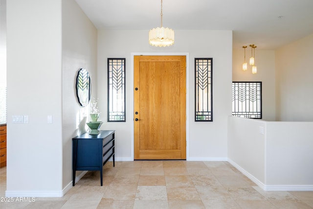 foyer featuring baseboards and an inviting chandelier