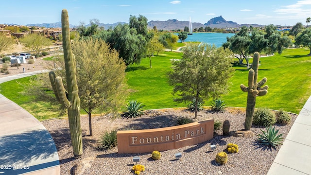 community / neighborhood sign with a lawn and a mountain view