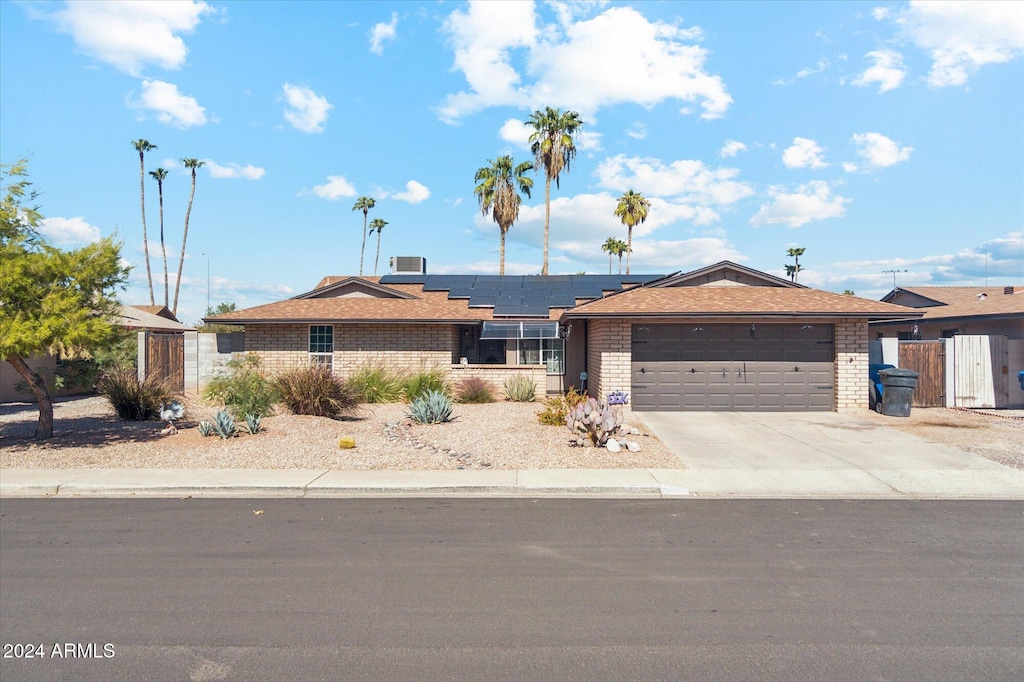 single story home with a garage and solar panels