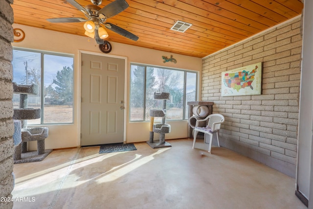 interior space featuring ceiling fan, wooden ceiling, and brick wall