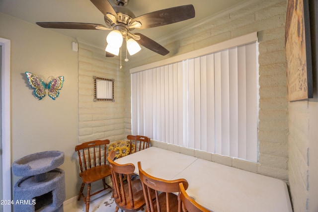 dining room with crown molding, ceiling fan, and brick wall