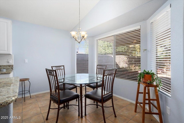 tiled dining area featuring an inviting chandelier and vaulted ceiling