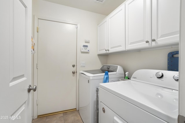 laundry area featuring washing machine and clothes dryer, light tile patterned flooring, and cabinets