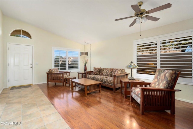 living room featuring ceiling fan, light wood-type flooring, and vaulted ceiling