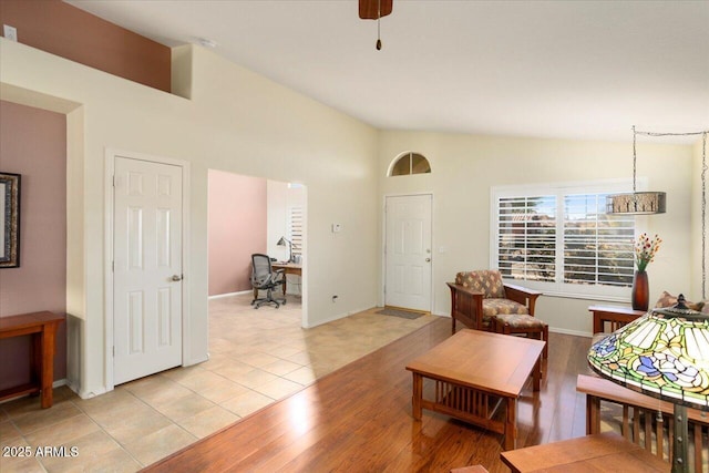 living room with ceiling fan, light tile patterned floors, and lofted ceiling