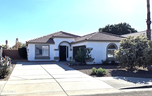 mediterranean / spanish house with a tiled roof, concrete driveway, an attached garage, and stucco siding