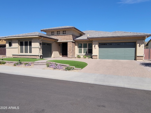 prairie-style house featuring decorative driveway, an attached garage, and stucco siding