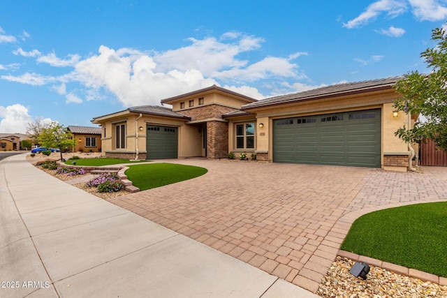 prairie-style home with an attached garage, decorative driveway, and stucco siding