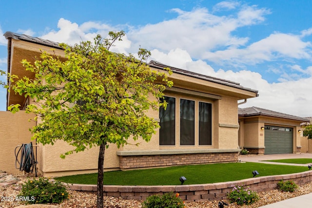 view of side of home with a garage, concrete driveway, a lawn, and stucco siding