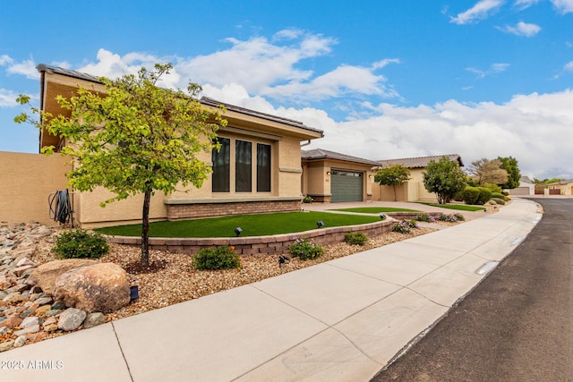 view of front of home featuring concrete driveway, an attached garage, roof mounted solar panels, and stucco siding