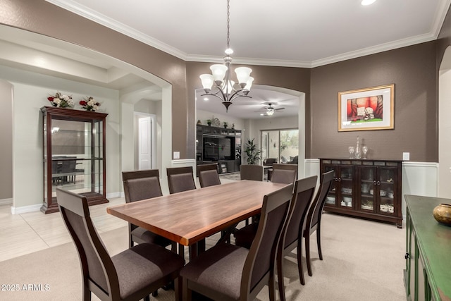 dining area featuring arched walkways, ceiling fan with notable chandelier, light carpet, and crown molding