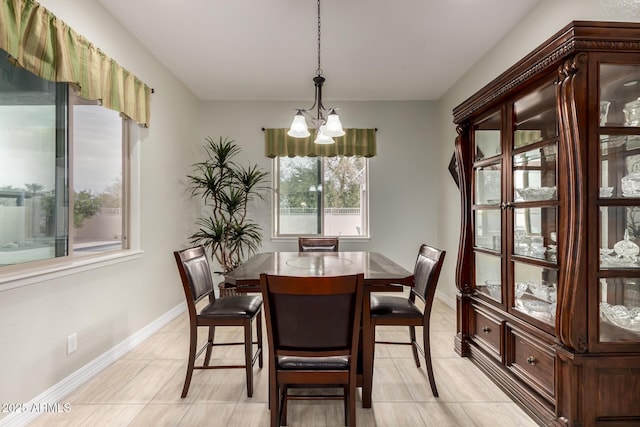 dining area with baseboards, a chandelier, and light tile patterned flooring