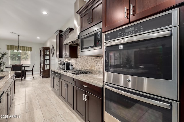 kitchen featuring appliances with stainless steel finishes, light stone countertops, wall chimney range hood, and tasteful backsplash