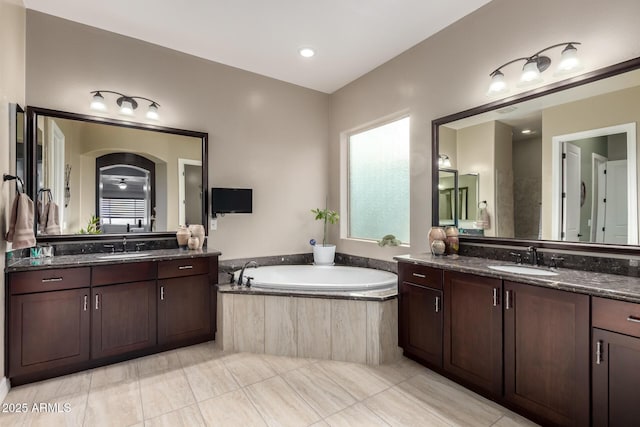 full bathroom with two vanities, a sink, and a bath