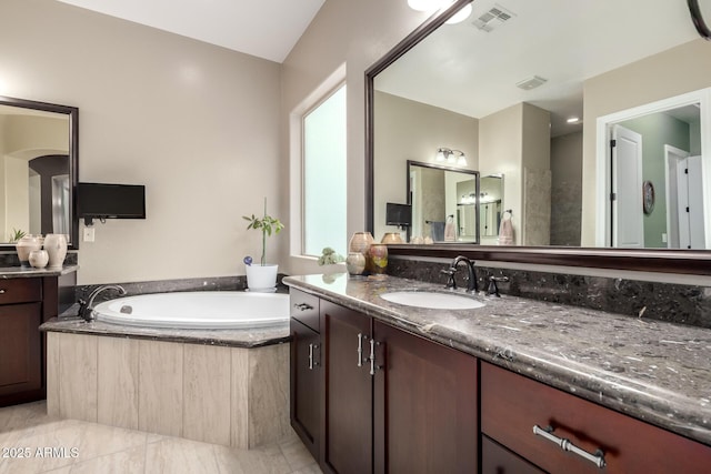 bathroom featuring visible vents, a bath, and vanity