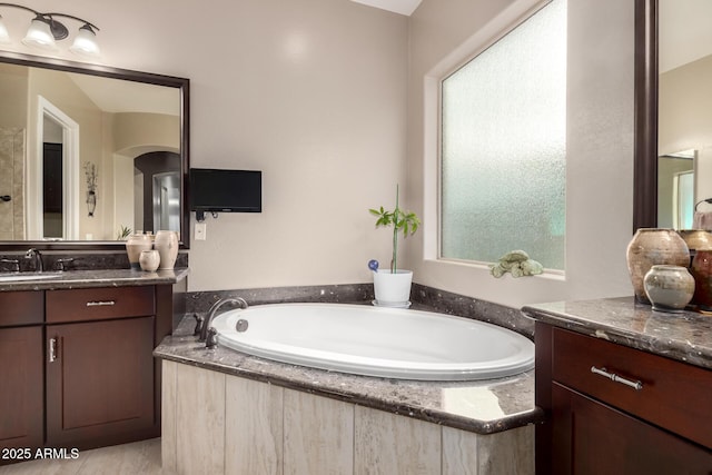 bathroom featuring a wealth of natural light, a garden tub, and vanity
