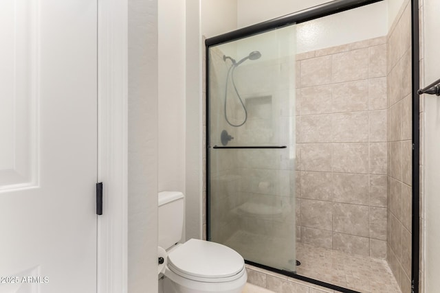 bathroom featuring toilet and a shower stall