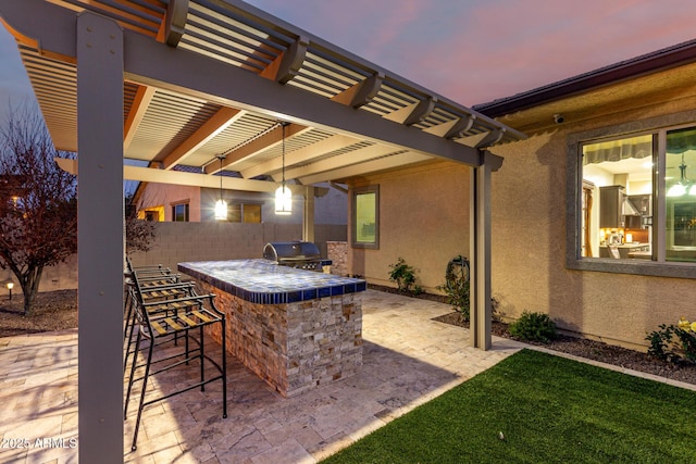 patio terrace at dusk with outdoor wet bar, area for grilling, fence, a grill, and a pergola