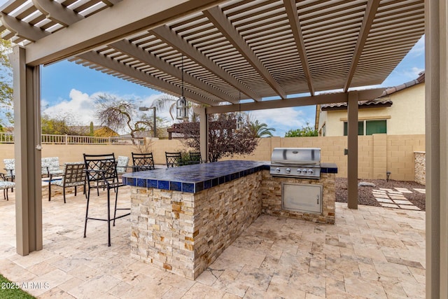 view of patio with a fenced backyard, outdoor dry bar, and area for grilling