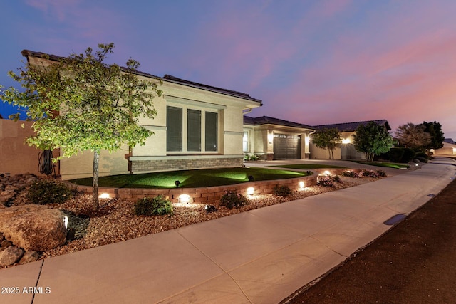 view of front facade with driveway, brick siding, an attached garage, and stucco siding