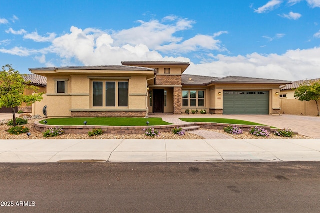 prairie-style home with driveway, brick siding, an attached garage, and stucco siding