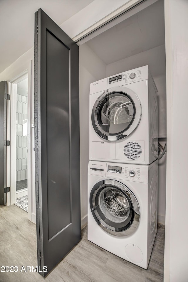 clothes washing area featuring light hardwood / wood-style floors and stacked washing maching and dryer