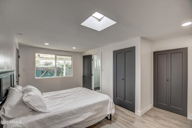 bedroom with a skylight, light hardwood / wood-style flooring, and ensuite bath