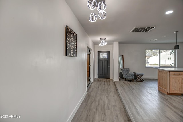 foyer entrance with light hardwood / wood-style floors and an inviting chandelier