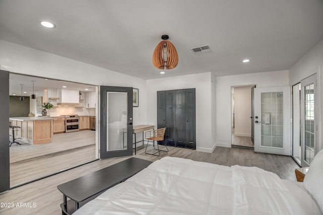 bedroom with french doors and light hardwood / wood-style flooring