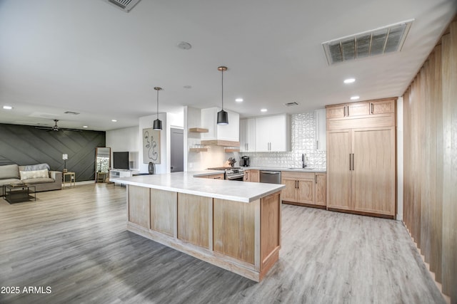 kitchen with kitchen peninsula, decorative light fixtures, light brown cabinetry, white cabinets, and appliances with stainless steel finishes