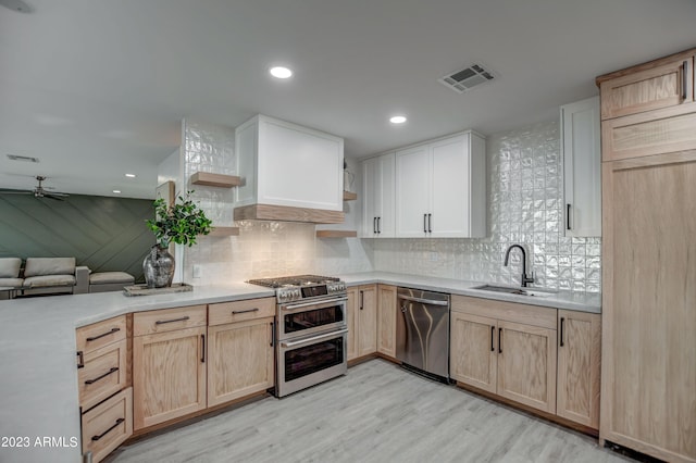 kitchen with stainless steel appliances, ceiling fan, sink, light brown cabinets, and light hardwood / wood-style floors