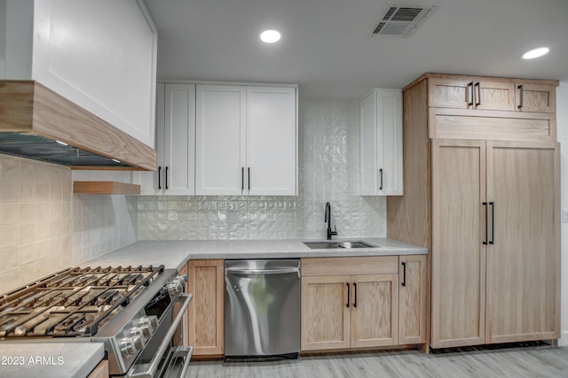 kitchen featuring backsplash, custom range hood, premium appliances, sink, and light brown cabinets