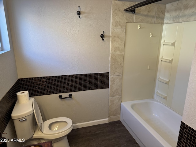 bathroom with wood-type flooring, washtub / shower combination, and toilet