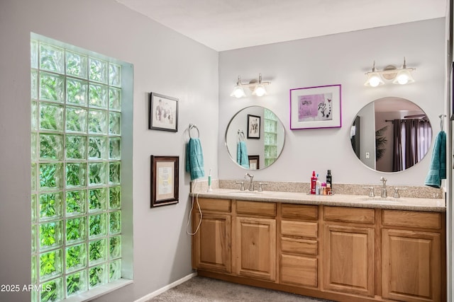 bathroom with a healthy amount of sunlight, a sink, baseboards, and double vanity