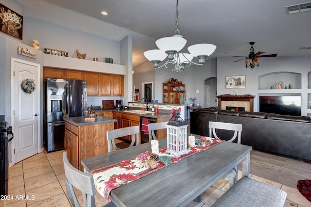 dining room featuring light tile patterned floors, ceiling fan with notable chandelier, vaulted ceiling, and sink