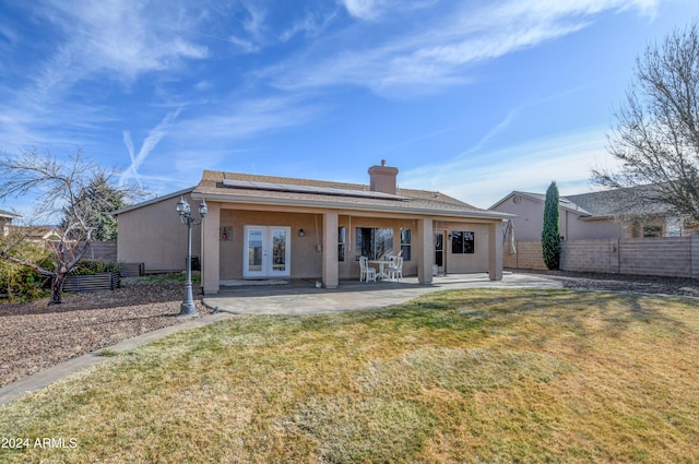 back of property featuring french doors, a yard, solar panels, and a patio