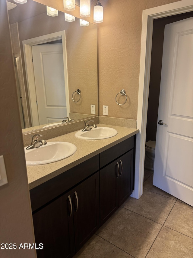 full bathroom featuring tile patterned flooring, a sink, double vanity, and toilet