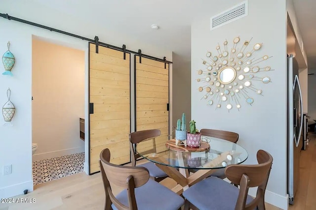 dining space with light wood-type flooring and a barn door