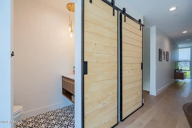 hallway with a barn door and light wood-type flooring