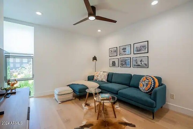 living room with ceiling fan, a wall of windows, and light hardwood / wood-style flooring