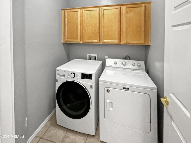 laundry room with light tile patterned flooring, cabinets, and washing machine and clothes dryer