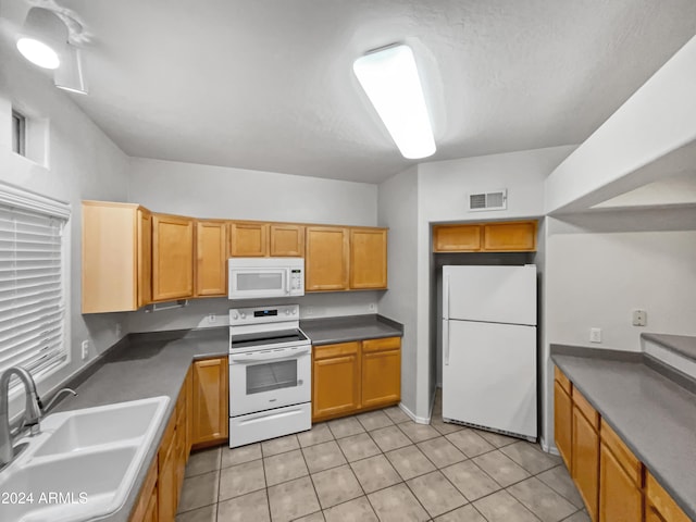 kitchen with white appliances, sink, and light tile patterned floors