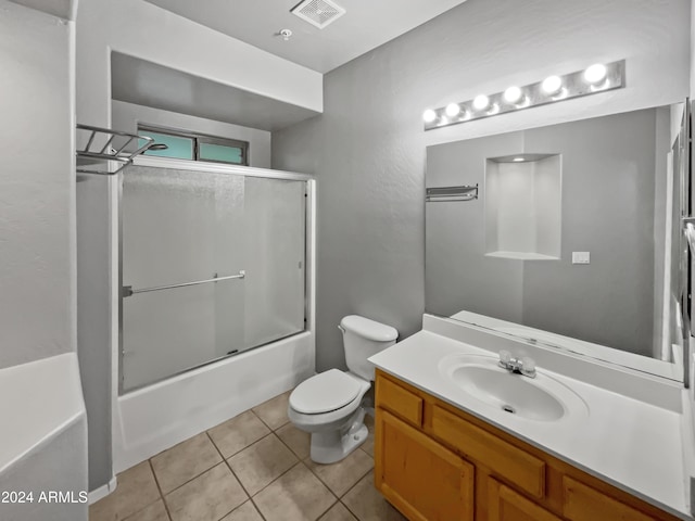 full bathroom featuring toilet, vanity, tile patterned floors, and enclosed tub / shower combo