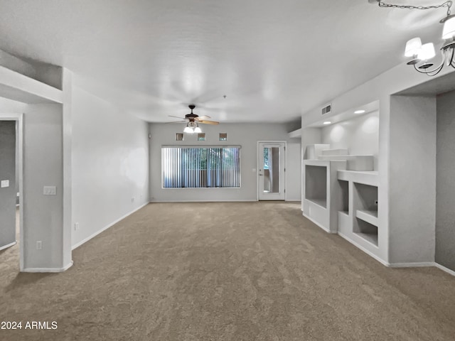 unfurnished living room featuring carpet flooring and ceiling fan with notable chandelier