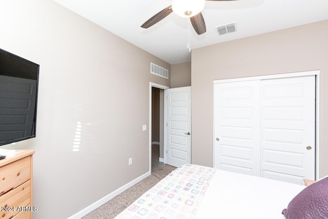 bedroom with ceiling fan, light carpet, and a closet