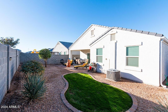 back of house featuring central AC unit and a lawn