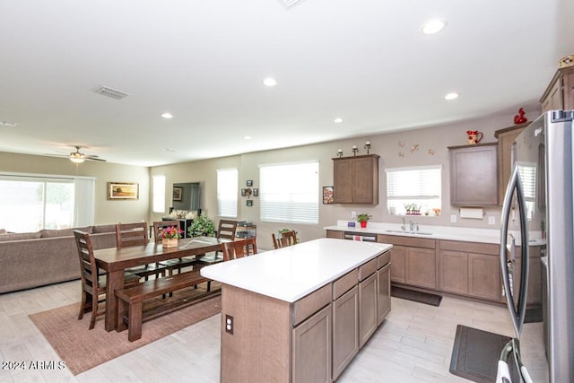 kitchen featuring ceiling fan, stainless steel fridge, a kitchen island, and plenty of natural light