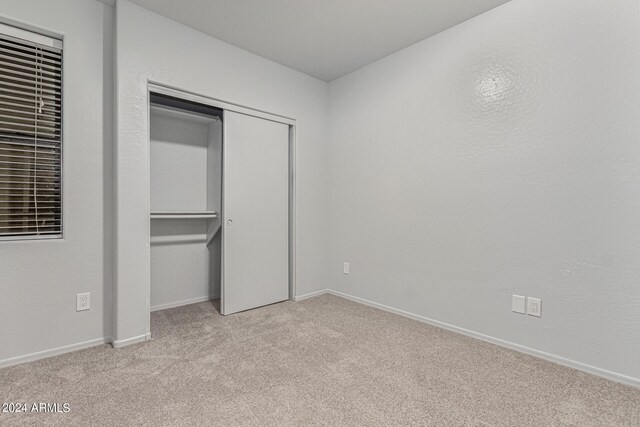 unfurnished bedroom featuring a closet and light carpet