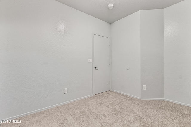 unfurnished room featuring light carpet and a textured ceiling