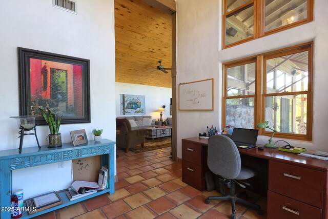 office space with visible vents, a high ceiling, and ceiling fan